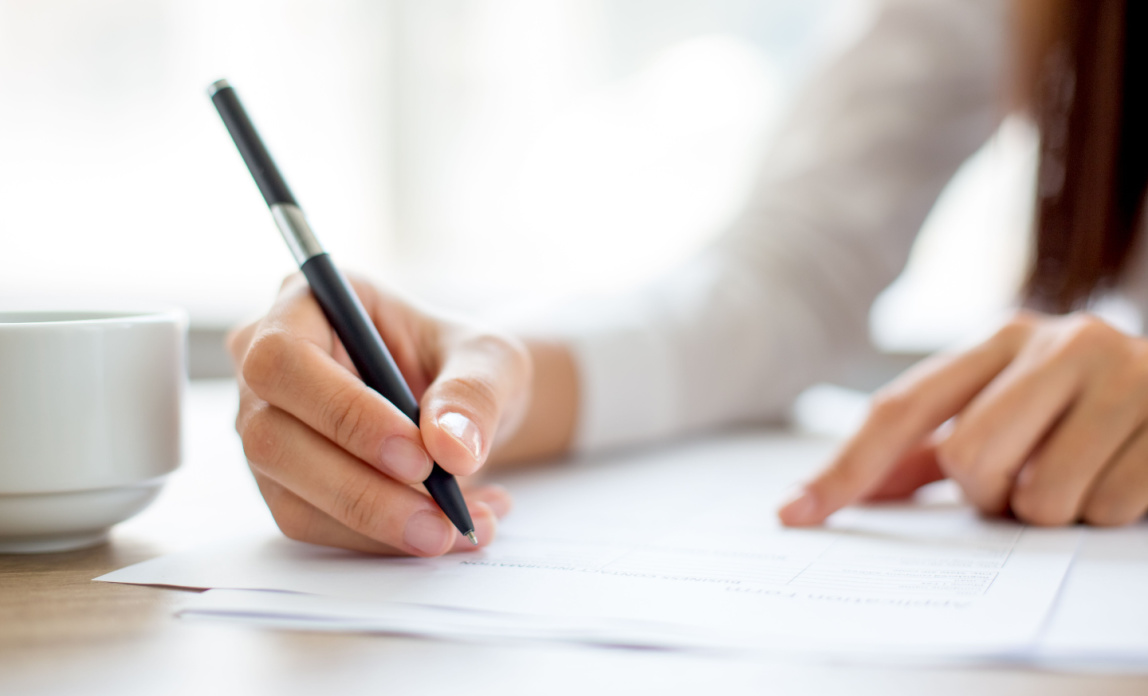 A person signing a contract with a pen