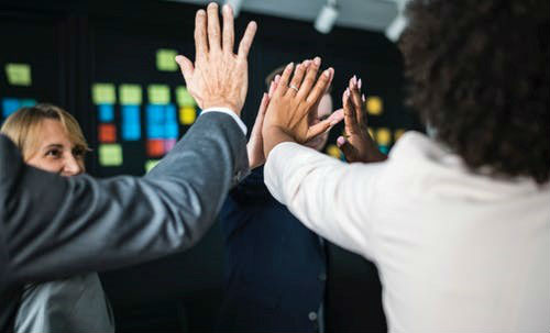 Team of IT workers give each other hi fives in support of each other