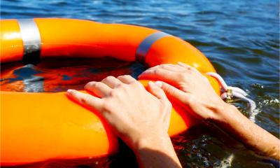 Person in the water holding onto a orange lifebuoy ring