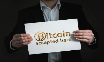 A man holds a card saying Bitcoin accepted