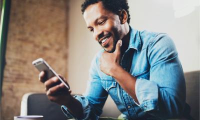 A happy bearded African businessman reads a blog feed