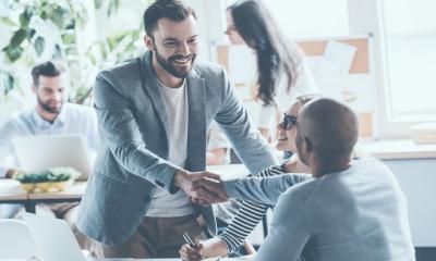 A business owner congratulates a successful worker and shows appreciation in the office.