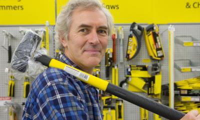 Builder holding yellow sledge hammer in hardware store