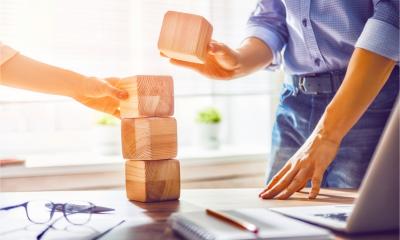 Two businesspeople build a tower of wooden blocks