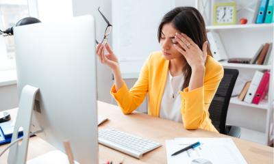 Businesswoman having head pain in office wring a bright orange jacket