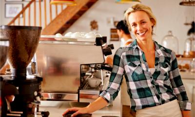 A smiling proud café owner starts work in her newly purchased business