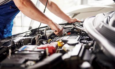 A mechanic looks under the bonnet of a car to assess the fault