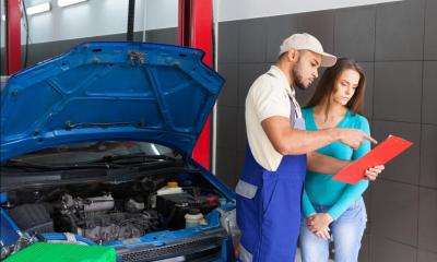 Car mechanic and customer stood next to car