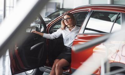 A smiling entrepreneur sits in her company car, which has been carefully chosen to give the right impression of her business.