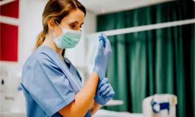 A female keyworker puts on her gloves before dealing with a patient