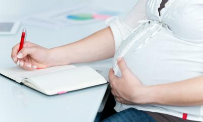 Pregnant women writing in her notebook on her white desk