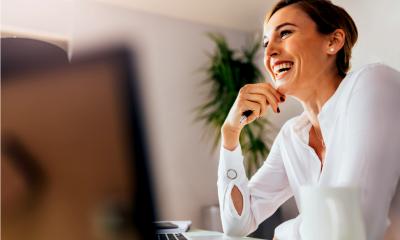 Woman with short hair in a white shirt smiling whilst holding a pen