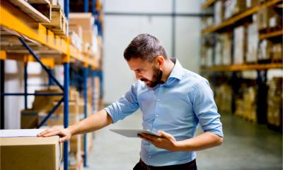 A manager in a fulfilment centre checks inventory for packing and shipping ecommerce orders
