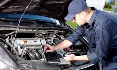 Car mechanic using a laptop as a OBD2 scanner tool