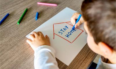 A child draws a house containing the words stay home