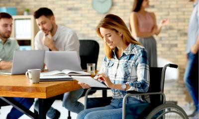 Young woman in wheelchair and colleagues at workplace Young woman in wheelchair and colleagues at workplace