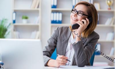 Business women on the phone at her desk wearing a grey suit