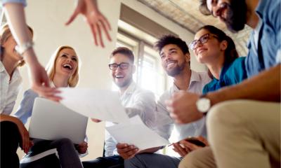 A group of happy employees laugh and joke in a meeting.