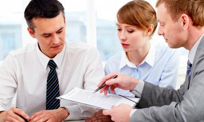 Holding a disciplinary hearing - checklist A business woman and two business men look at a checklist