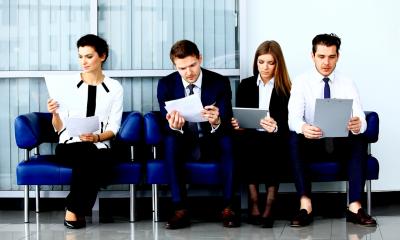 Holding successful recruitment interviews - checklist Two women and two men wearing business clothes sit reading a piece of paper