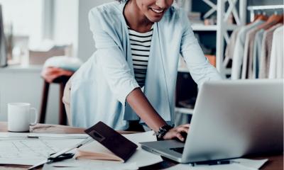 Woman in a blue top using her laptop to get trade sale ready