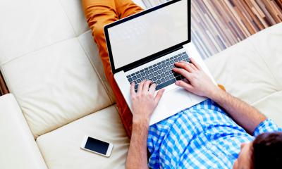 Man using his laptop for part-time work while sitting down on the sofa