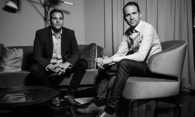 Black and white photo of two men say down on a chair and sofa