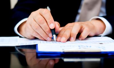 Close up of male hands holding a pen writing on paper