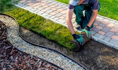 Man unrolling grass while landscaping a garden