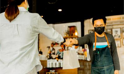 A waiter gives food to a client in a small food business. Social distance concept.