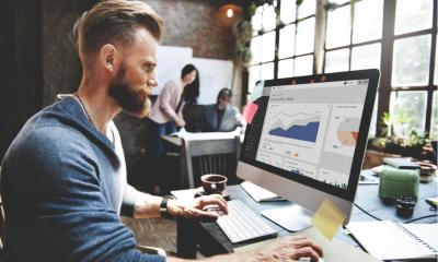 Businessman sat in front of a computer screen looking at financial analysis graphs