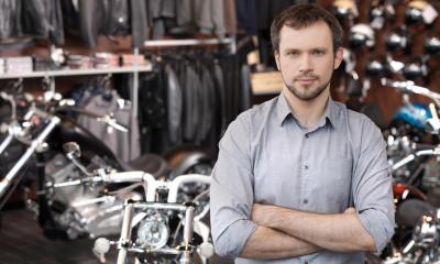 Motorsykkel forhandler i sin butikk med motorsykler og motorsykkel kit i bakgrunnen