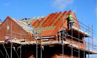 A worker from a building firm standing on scaffolding outside a house