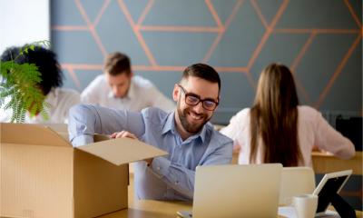 Smiling employees unpack their boxes full of work equipment in a smart new office.