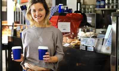 Femme tenant deux tasses de café en carton devant till
