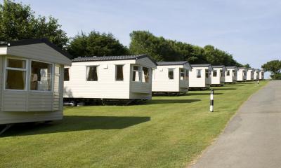 Multiple white caravans on grass on a sunny day with blue sky