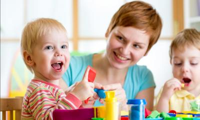 Woman looking after two children playing with toys