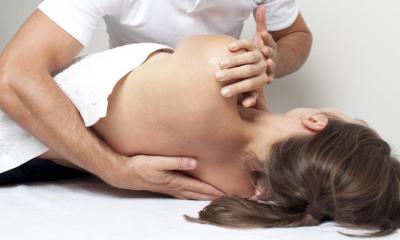 Woman lying on her side being moved into position by male chiropractor