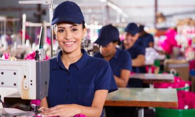 Woman in blue cap working in factory using sewing machine