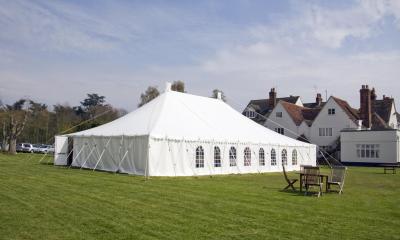 White marquee in grass field with houses in background