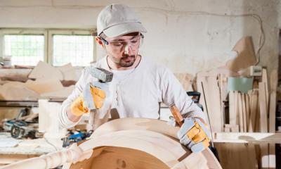 Man in cap building table in furniture making workshop
