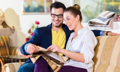 Man and woman sitting on sofa looking at piece of material