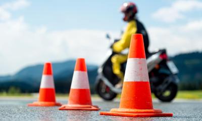 Yellow motorcycle rider driving round three orange and white cones