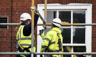 Scaffolders in high visibility jackets working by a window