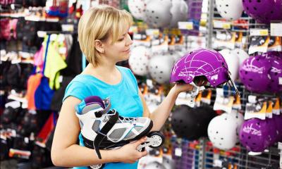 Woman holding roller blade and purple helmet in sports shop