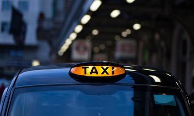 Black taxi with 'TAXI' sign lit up during night-time