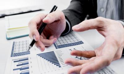 Man holding a pen writing on an investment sheet of paper