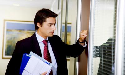 Man in a suit about to knock on a door to have a difficult conversation with an empployee