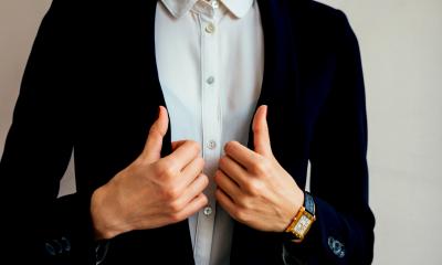Woman in a white shirt and navy jacket wearing a black and gold watch