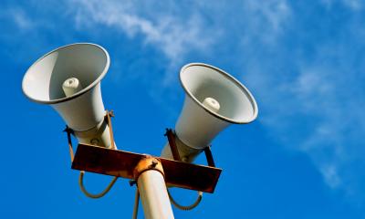 Two warning sirens on a clear day with a blue sky in the background